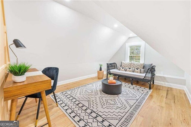 living area featuring lofted ceiling and hardwood / wood-style flooring