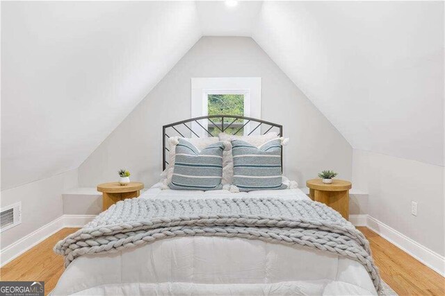 bedroom with vaulted ceiling and hardwood / wood-style flooring