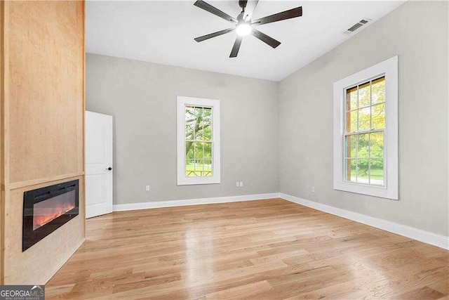 unfurnished living room featuring ceiling fan, light hardwood / wood-style floors, and a healthy amount of sunlight