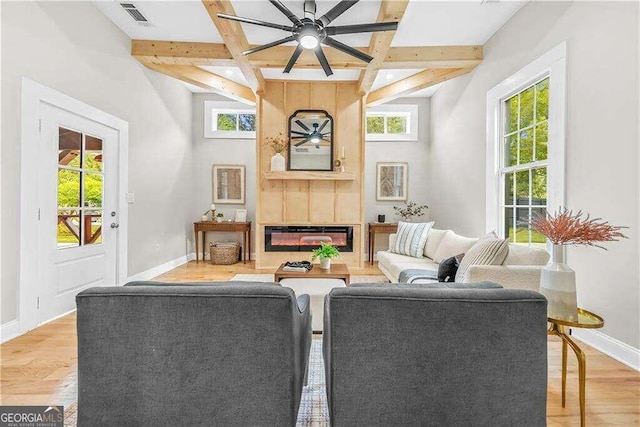 living room with beamed ceiling, hardwood / wood-style floors, ceiling fan, and plenty of natural light