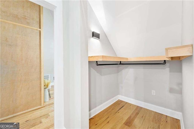 walk in closet featuring wood-type flooring and lofted ceiling