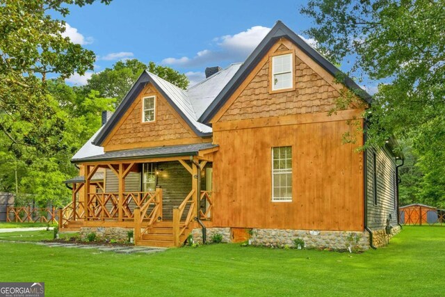 back of property with a porch, a yard, and a shed