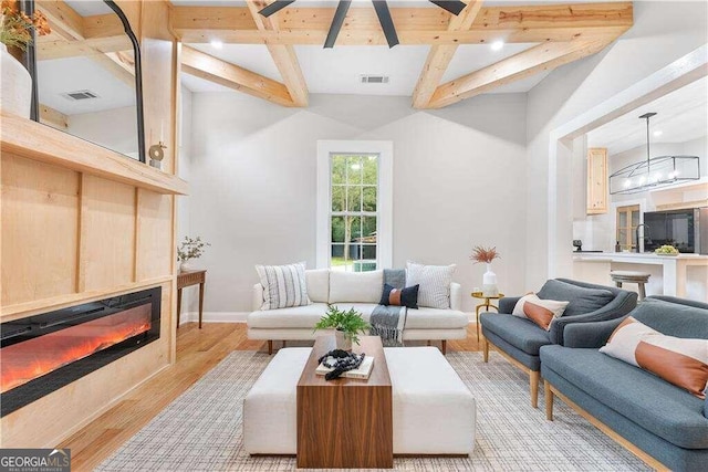 living room with light wood-type flooring and beamed ceiling