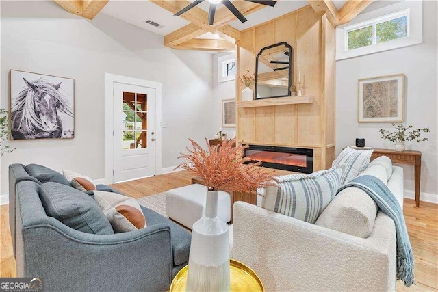 living room featuring light wood-type flooring, beam ceiling, ceiling fan, and a high ceiling