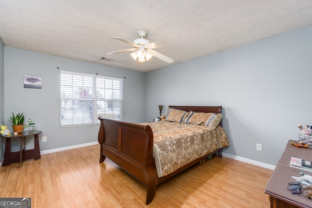 bedroom with ceiling fan, hardwood / wood-style flooring, and a textured ceiling