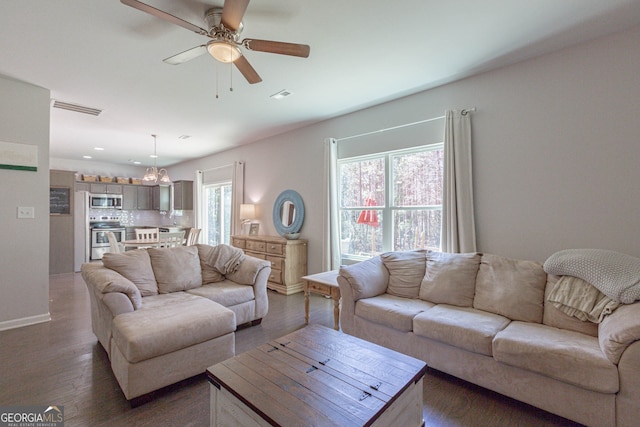 living room featuring ceiling fan and dark wood-type flooring