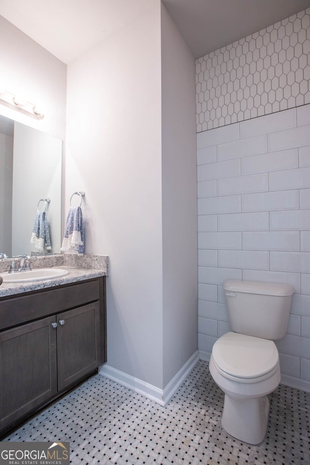 bathroom with tile walls, vanity, and toilet