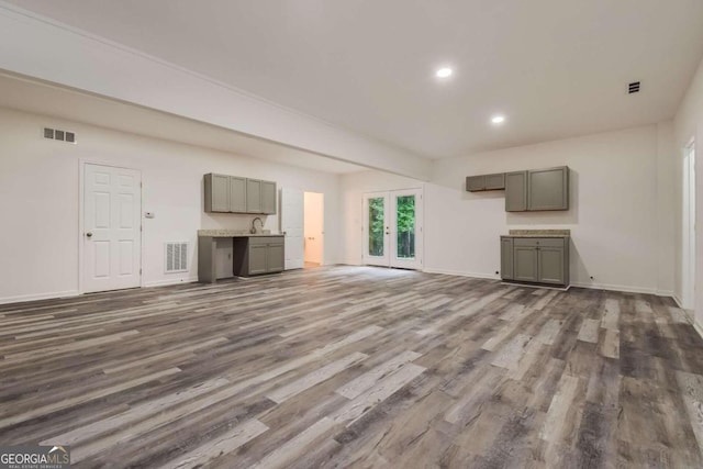 unfurnished living room featuring french doors, sink, and dark hardwood / wood-style flooring