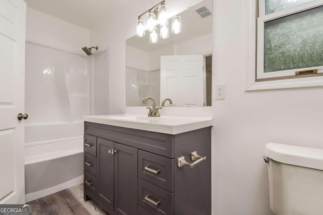 full bathroom featuring washtub / shower combination, hardwood / wood-style floors, vanity, and toilet