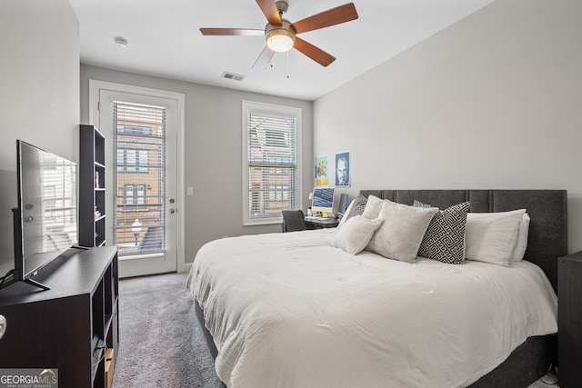 bedroom with multiple windows, ceiling fan, dark carpet, and access to outside