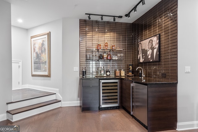 bar with stainless steel refrigerator, beverage cooler, hardwood / wood-style floors, sink, and decorative backsplash