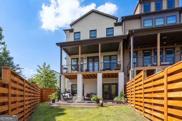 rear view of house featuring a balcony, a lawn, and a patio area