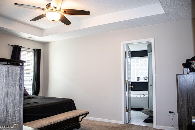 carpeted bedroom with a textured ceiling, ceiling fan, ensuite bathroom, and multiple windows