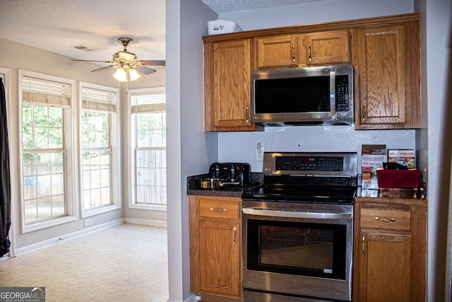 kitchen with appliances with stainless steel finishes, a textured ceiling, light colored carpet, and ceiling fan