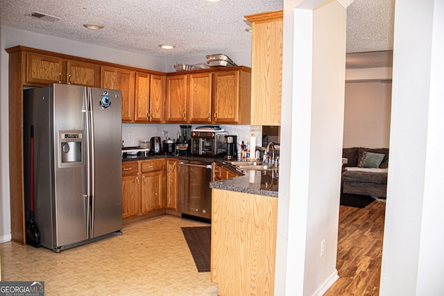 kitchen featuring a textured ceiling, stainless steel appliances, light hardwood / wood-style floors, and sink