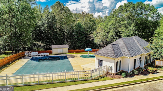 view of pool with a patio and a shed