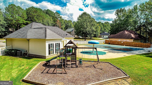 view of playground featuring central AC unit, a covered pool, and a lawn