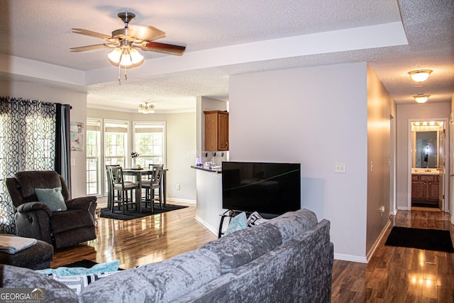 living room with a textured ceiling, ceiling fan, and dark wood-type flooring