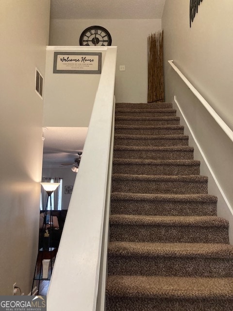 stairs featuring ceiling fan