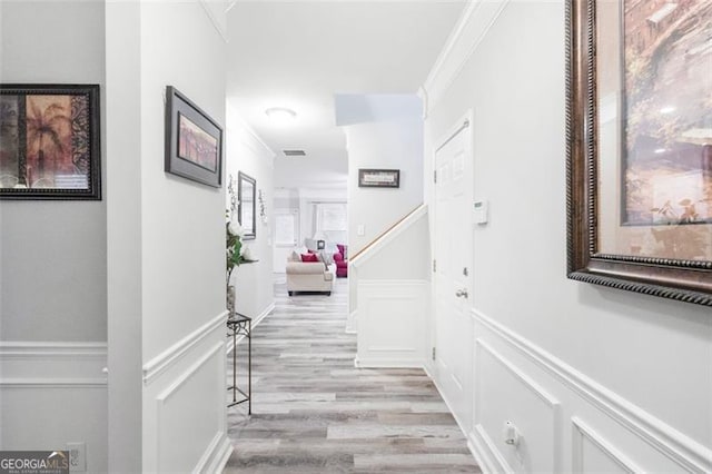 hallway featuring ornamental molding and light hardwood / wood-style floors