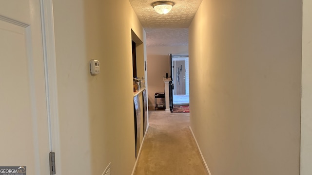 hallway featuring light carpet and a textured ceiling