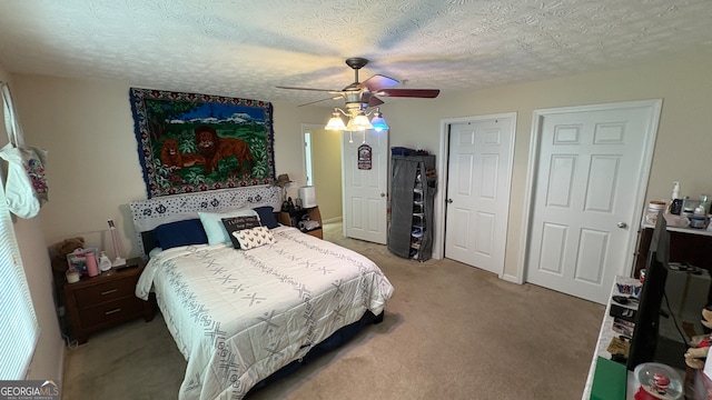 carpeted bedroom featuring ceiling fan and a textured ceiling