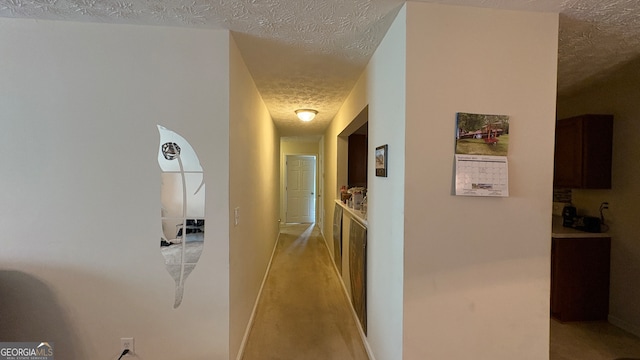 corridor with light carpet and a textured ceiling