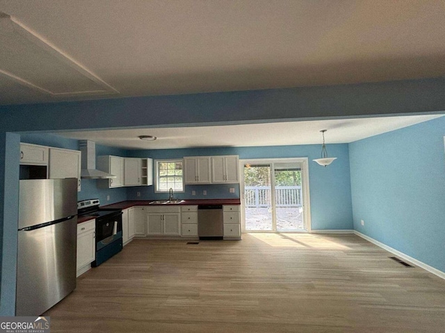 kitchen featuring wall chimney exhaust hood, white cabinets, appliances with stainless steel finishes, and sink