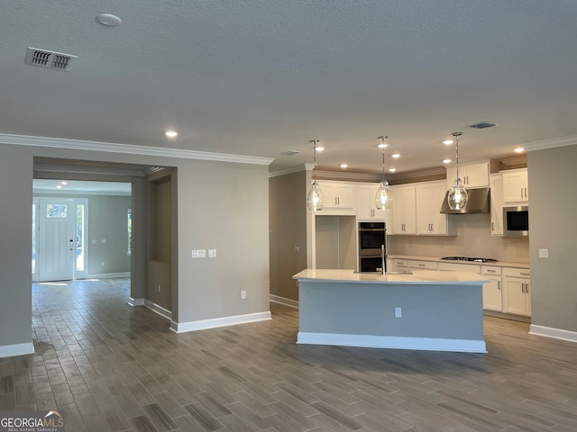 kitchen featuring a center island with sink, white cabinetry, pendant lighting, and stainless steel double oven