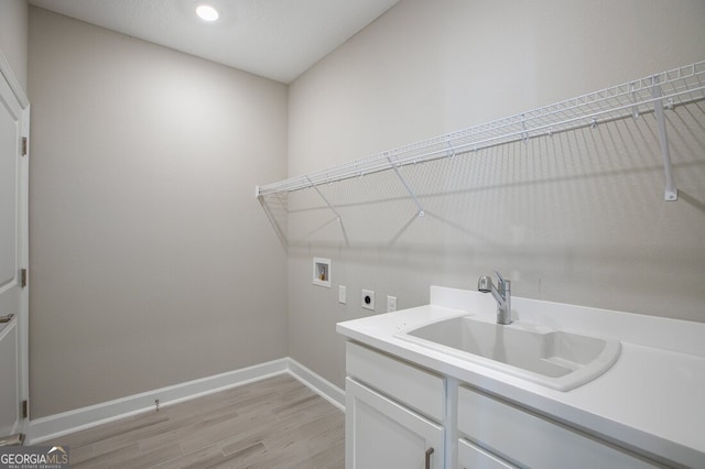 laundry room with sink, washer hookup, electric dryer hookup, and light hardwood / wood-style flooring