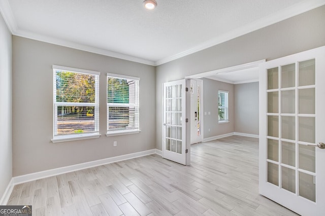 spare room with ornamental molding, french doors, and light hardwood / wood-style floors