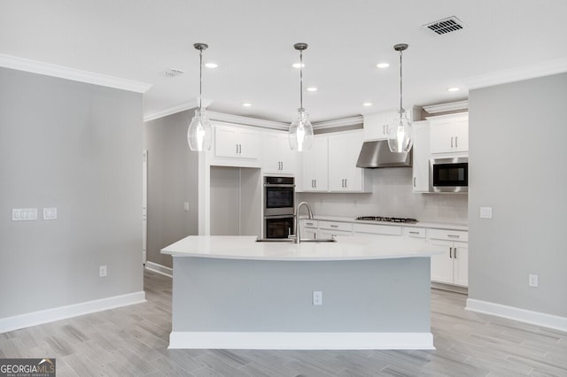 kitchen featuring a kitchen island with sink, white cabinets, and stainless steel appliances