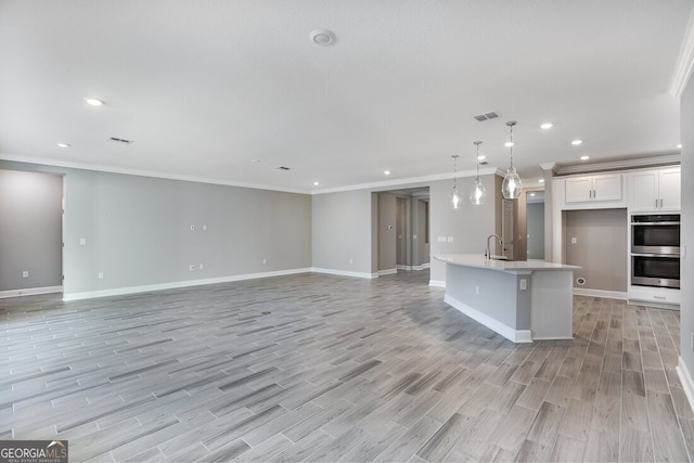 kitchen with white cabinetry, an island with sink, stainless steel double oven, decorative light fixtures, and sink