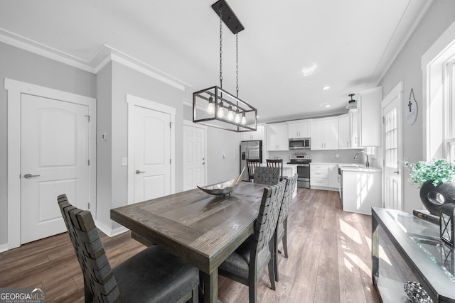 dining room featuring a notable chandelier, dark hardwood / wood-style floors, sink, and crown molding