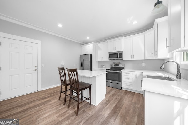 kitchen featuring white cabinets, stainless steel appliances, sink, and a kitchen island