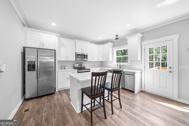 kitchen with a kitchen island, light hardwood / wood-style floors, white cabinetry, and stainless steel appliances