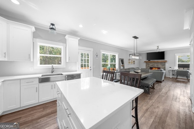 kitchen with white cabinets, a fireplace, sink, and a center island