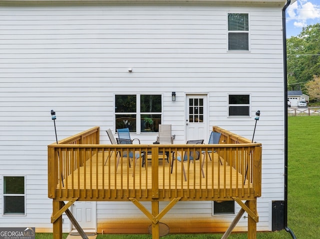 back of property featuring a wooden deck and a yard