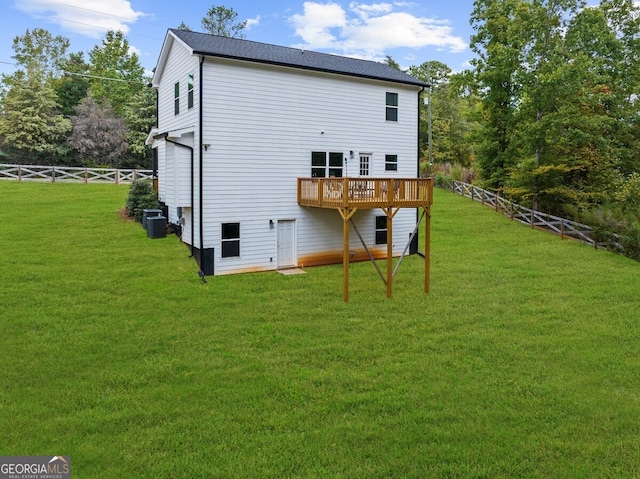 rear view of property featuring cooling unit, a deck, and a lawn