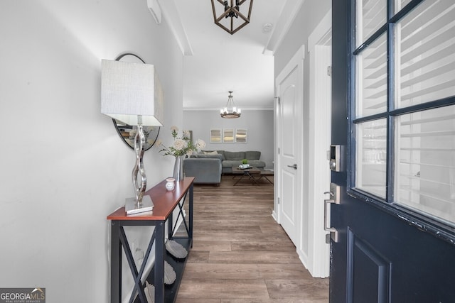 entryway with crown molding, dark hardwood / wood-style floors, and a notable chandelier