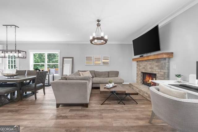 living room featuring a fireplace, ornamental molding, a chandelier, and hardwood / wood-style flooring