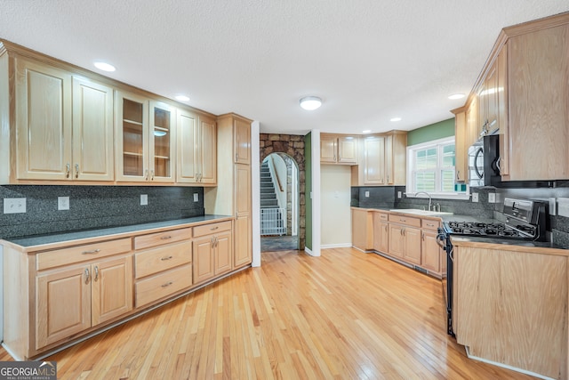 kitchen with a textured ceiling, sink, light hardwood / wood-style flooring, light brown cabinets, and black range with gas cooktop