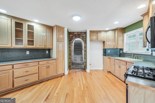 kitchen featuring sink, a textured ceiling, light hardwood / wood-style floors, and tasteful backsplash