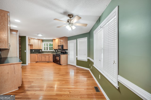 kitchen with decorative backsplash, a textured ceiling, light wood-type flooring, black gas stove, and sink