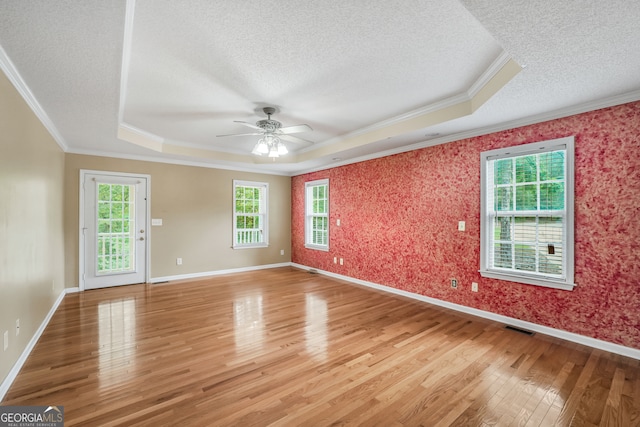 unfurnished room featuring a raised ceiling, a textured ceiling, crown molding, ceiling fan, and hardwood / wood-style floors