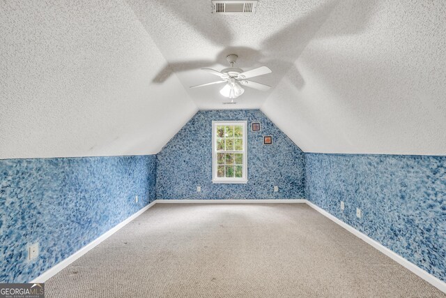 empty room with a textured ceiling, carpet, and ceiling fan