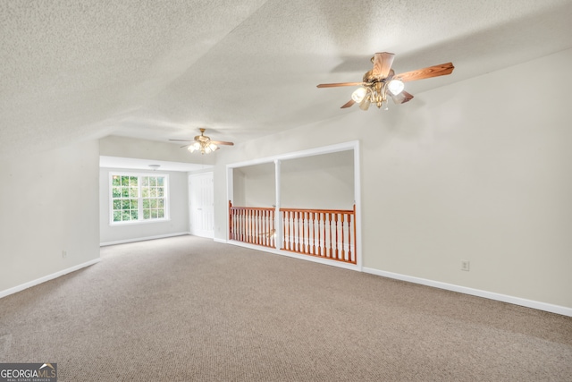 empty room with ceiling fan, a textured ceiling, lofted ceiling, and carpet