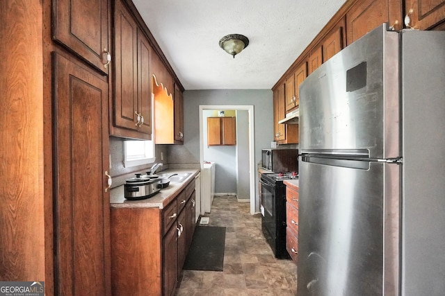 kitchen with a textured ceiling, stainless steel fridge, black / electric stove, and sink