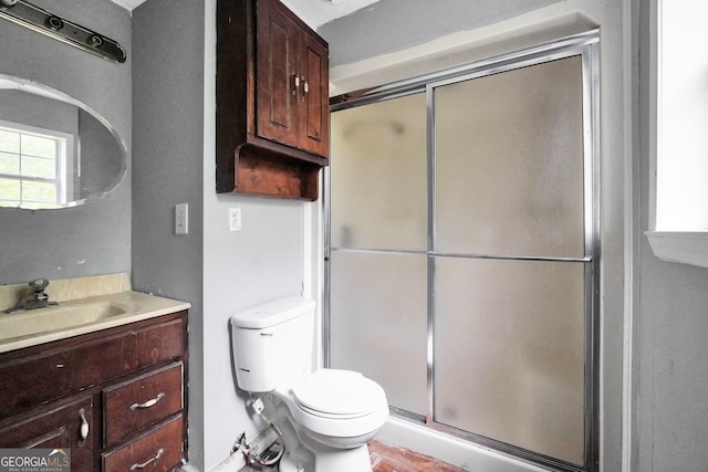 bathroom featuring vanity, toilet, and a shower with door