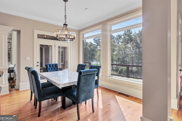 dining room featuring light hardwood / wood-style floors, ornamental molding, and an inviting chandelier